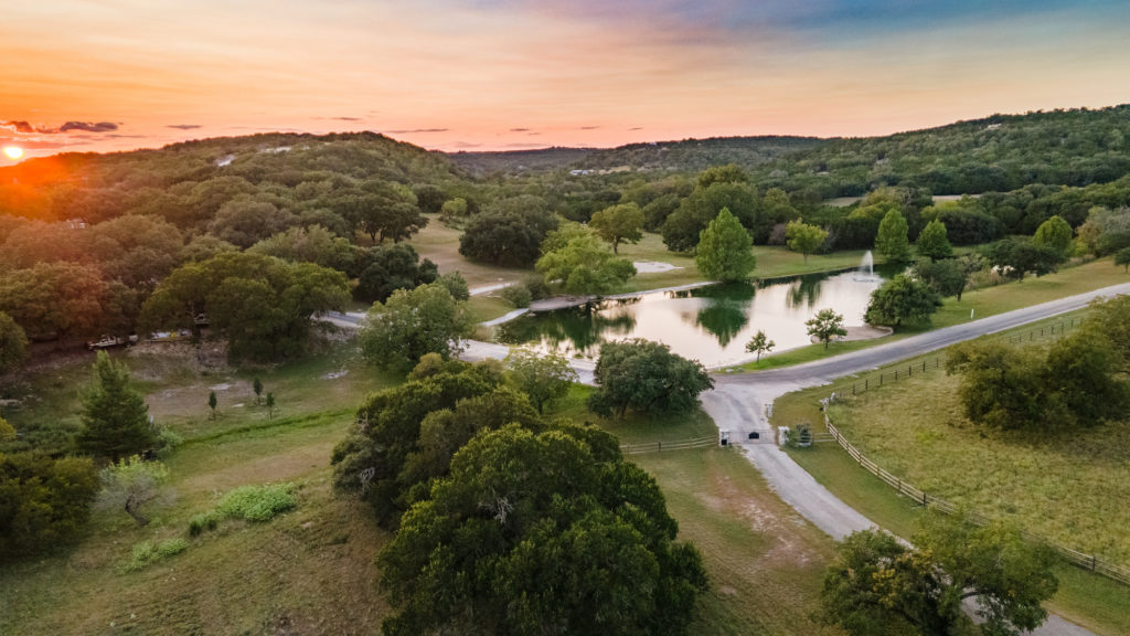 Aerial view at sunset of a lake surrounded by oak trees and a winding road