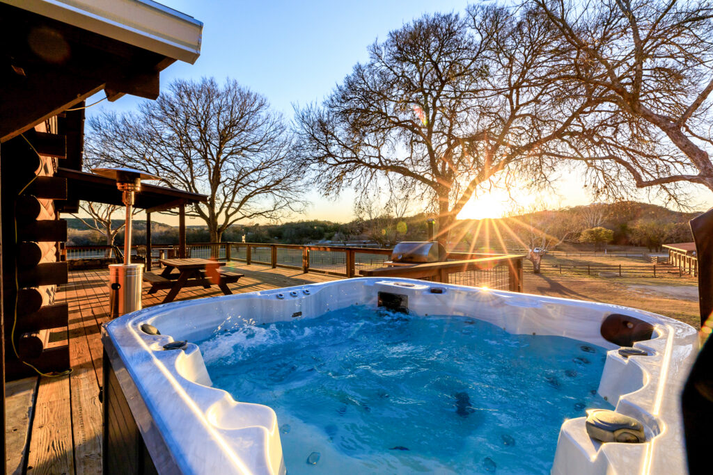 Hot tub on a wooden deck at sunset with oak trees in the background