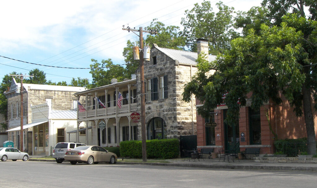Historic limestone buildings and shade trees along High Street in downtown Comfort, Texas